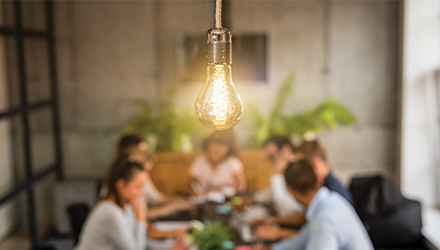 Lightbulb hanging above people in meeting