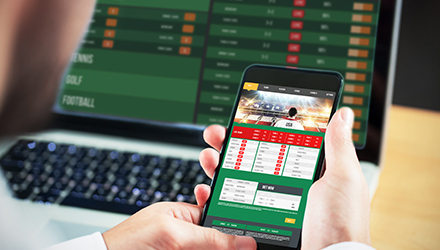 Person sports betting on phone and laptop