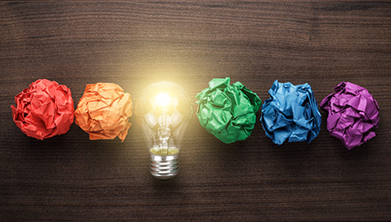 lightbulb surrounded by different color paper balls