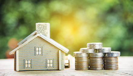 Small house next to stacks of coins