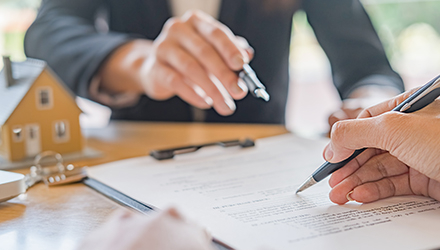 two individuals with pens over document