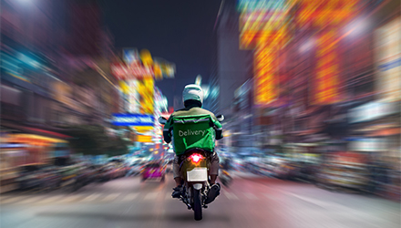 Delivery driver on a scooter traveling down a city street