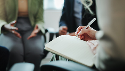 three people sitting and having a discussion while taking notes